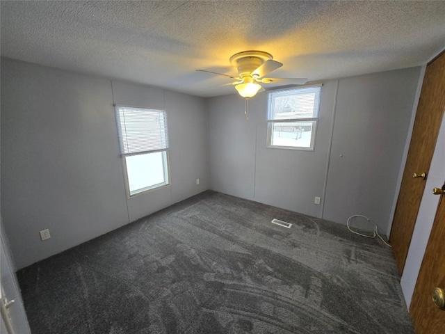 unfurnished room featuring ceiling fan, dark carpet, and a textured ceiling