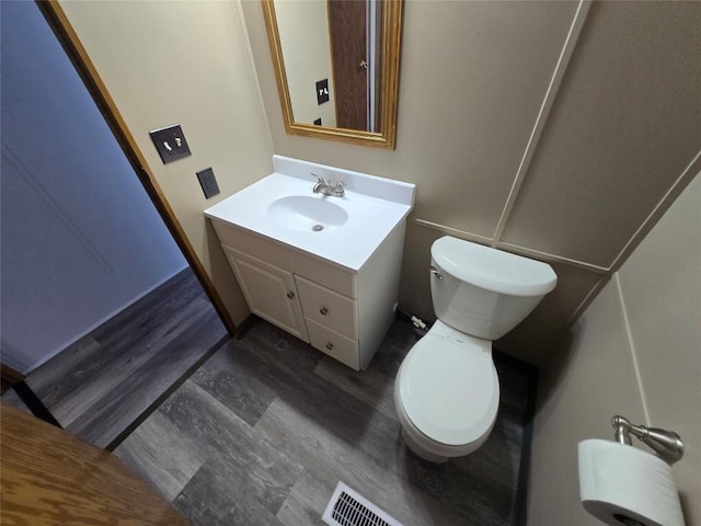 bathroom with hardwood / wood-style flooring, toilet, and vanity