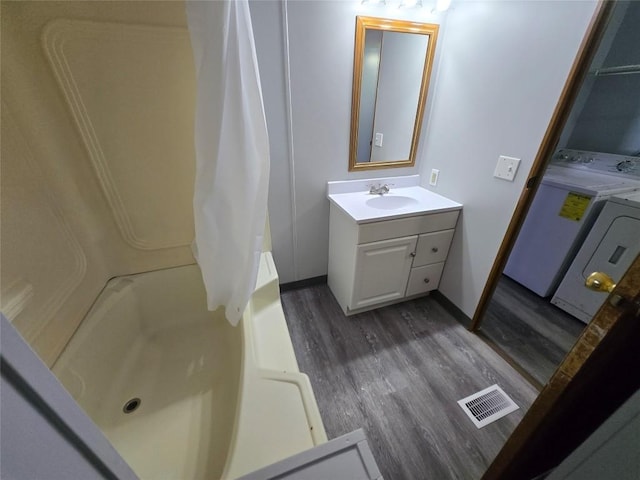 bathroom featuring vanity, shower / tub combo, washer and clothes dryer, and hardwood / wood-style floors