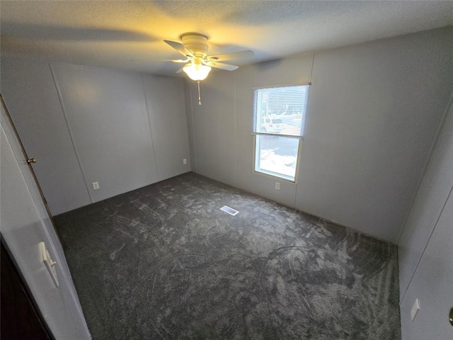 unfurnished room with ceiling fan and dark carpet