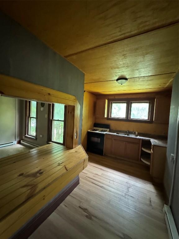 kitchen featuring light hardwood / wood-style floors, baseboard heating, a wealth of natural light, and gas range gas stove