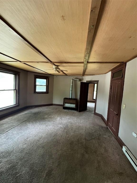 unfurnished room with beam ceiling, carpet floors, and a baseboard heating unit