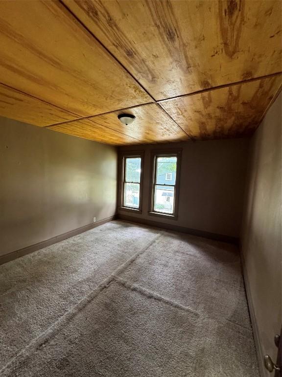 carpeted empty room featuring wooden ceiling