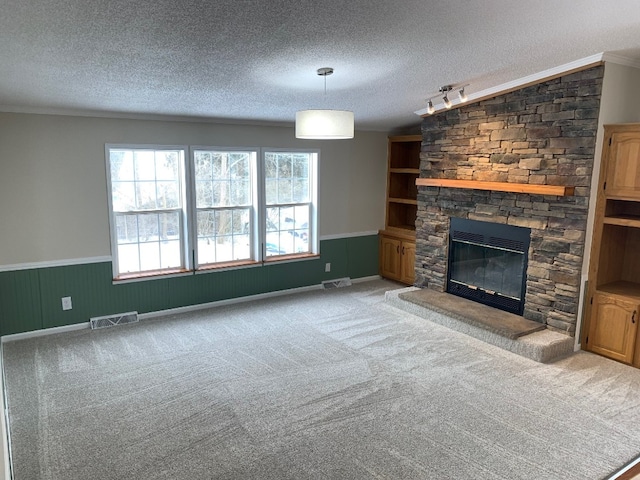 unfurnished living room featuring a textured ceiling, a wainscoted wall, a fireplace, and visible vents