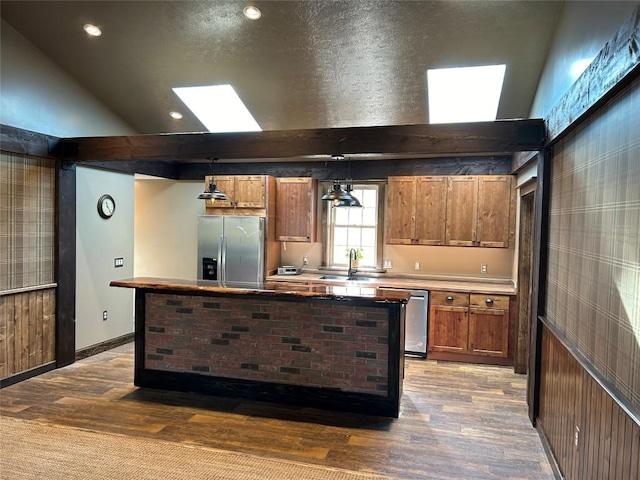 11667 Lakeland Dr, Conneaut Lake, PA 16316 - kitchen with a center island, brown cabinets, wood finished floors, a sink, and stainless steel appliances
