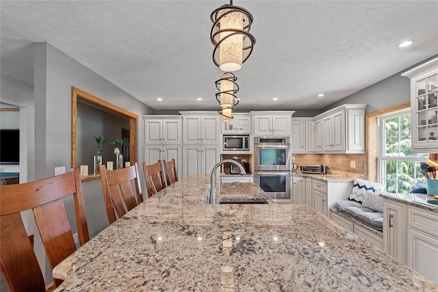 18376 Barber Rd, Meadville, PA 16335 - kitchen with appliances with stainless steel finishes, tasteful backsplash, white cabinets, light stone counters, and decorative light fixtures