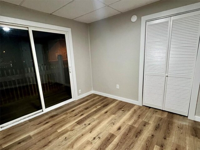 647-649 E 11th St, Erie, PA 16503 - unfurnished bedroom with wood finished floors, baseboards, a closet, and a paneled ceiling