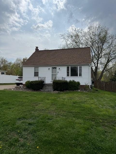 view of front of house featuring fence, a chimney, and a front lawn