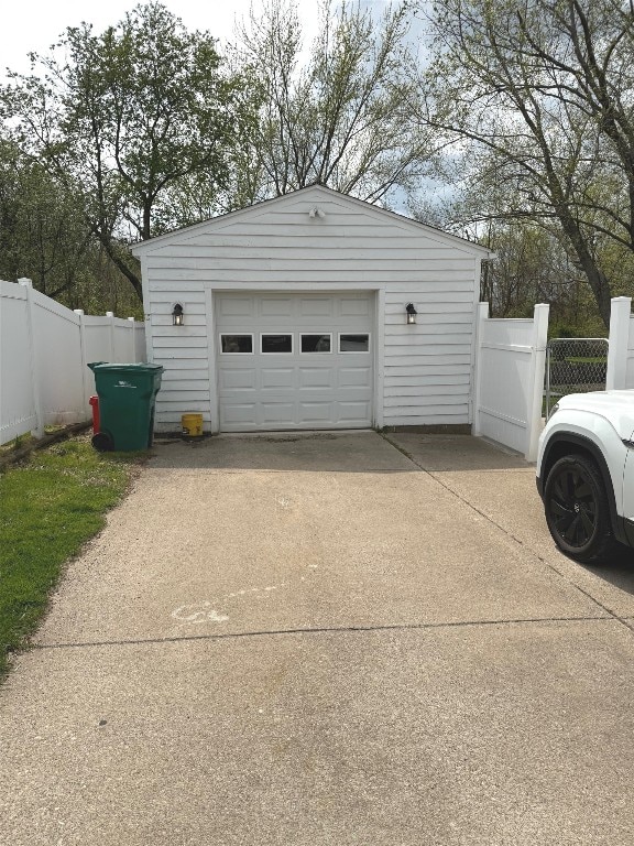 detached garage with concrete driveway and fence