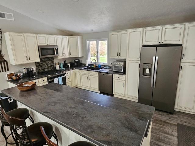 kitchen with a textured ceiling, decorative backsplash, lofted ceiling, and stainless steel appliances