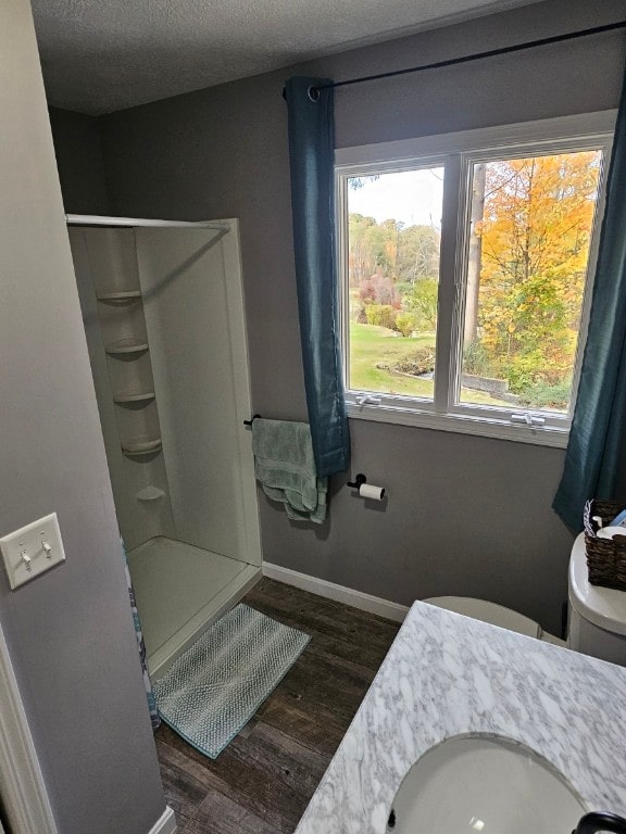 bathroom featuring walk in shower, hardwood / wood-style floors, a textured ceiling, toilet, and vanity