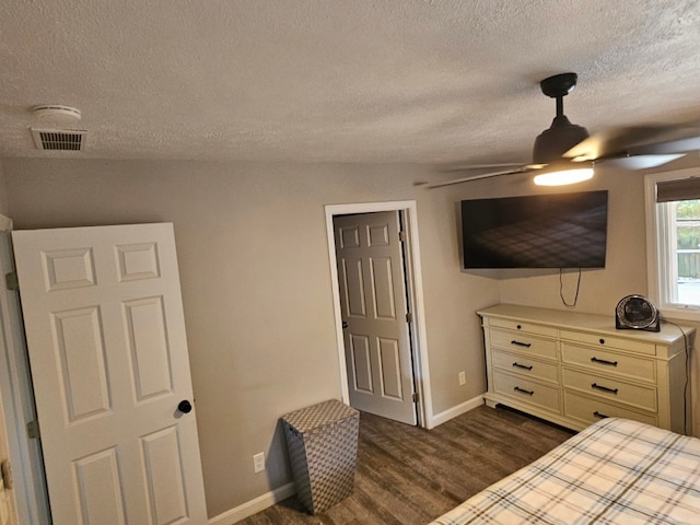 bedroom with a textured ceiling, ceiling fan, and dark wood-type flooring