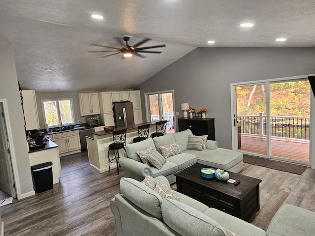 living room featuring a textured ceiling, ceiling fan, wood-type flooring, and vaulted ceiling