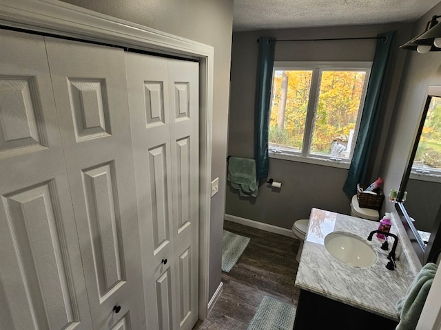 bathroom with hardwood / wood-style floors, vanity, toilet, and a textured ceiling