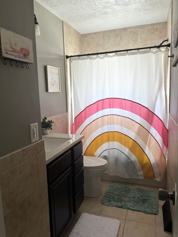 bathroom with vanity, walk in shower, toilet, tile patterned floors, and a textured ceiling