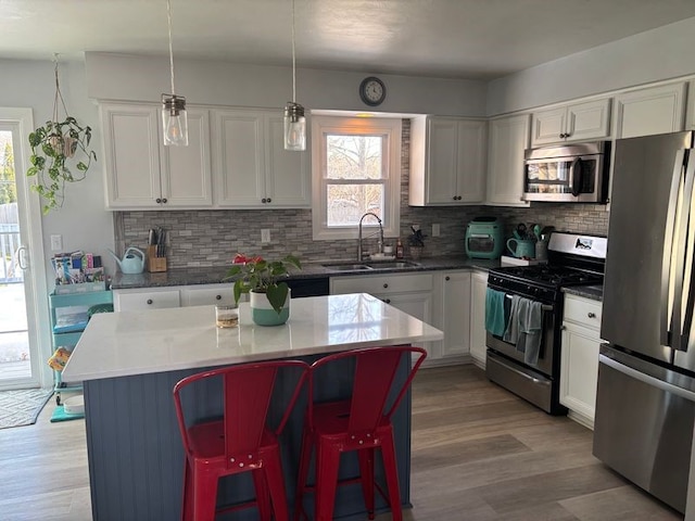 kitchen with white cabinetry, sink, stainless steel appliances, and a kitchen island