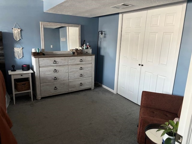 bedroom with dark colored carpet, a textured ceiling, and a closet