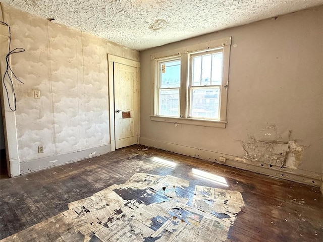unfurnished room with a textured ceiling and hardwood / wood-style flooring