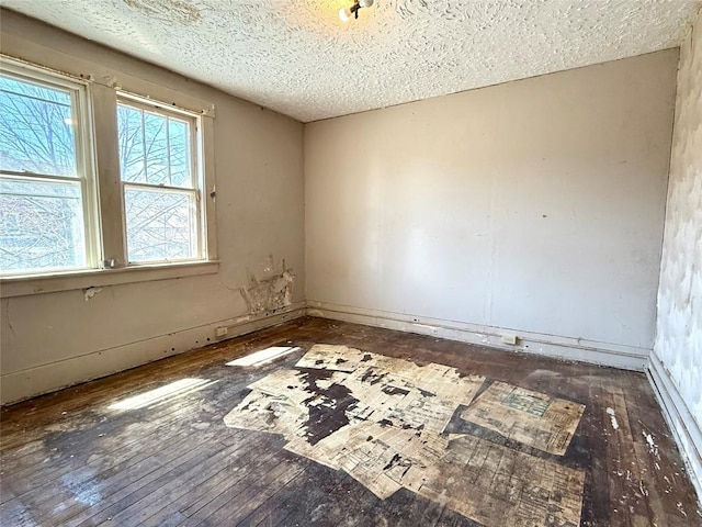 spare room with hardwood / wood-style flooring, baseboards, and a textured ceiling