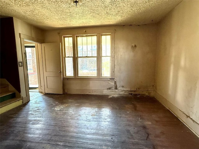 empty room with a textured ceiling, stairway, and wood-type flooring