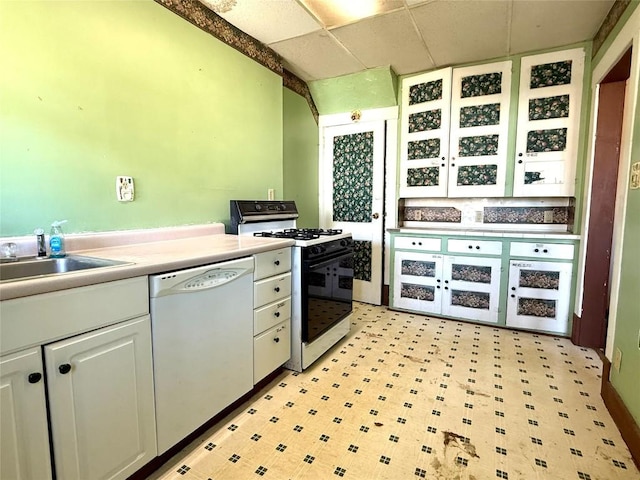 kitchen featuring white cabinets, a sink, white dishwasher, gas range, and a paneled ceiling