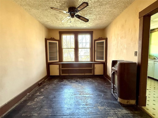 unfurnished room with a ceiling fan, a textured ceiling, a sink, wood-type flooring, and baseboards