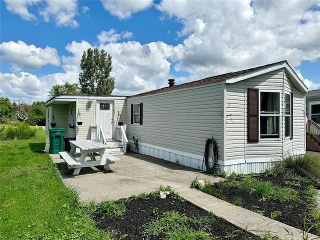 rear view of property featuring a yard and a patio area