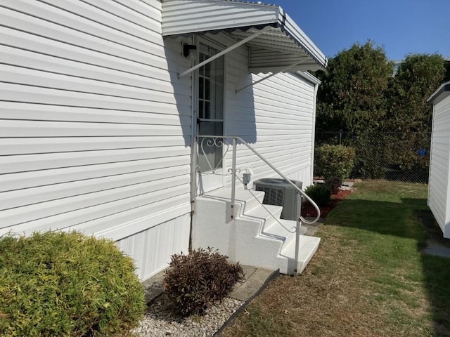 view of side of home featuring cooling unit and a yard