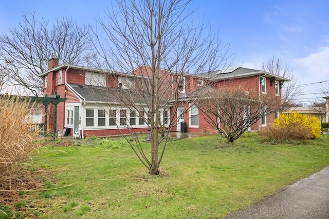 51-55 E Main St, North East, PA 16428 - view of front facade featuring brick siding, solar panels, a chimney, and a front yard