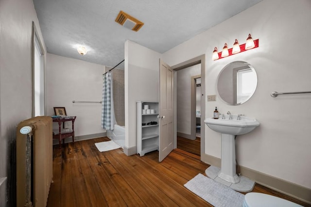 51-55 E Main St, North East, PA 16428 - bathroom featuring wood-type flooring, shower / bath combo, baseboards, toilet, and a sink