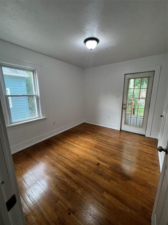 empty room with a textured ceiling and dark hardwood / wood-style flooring