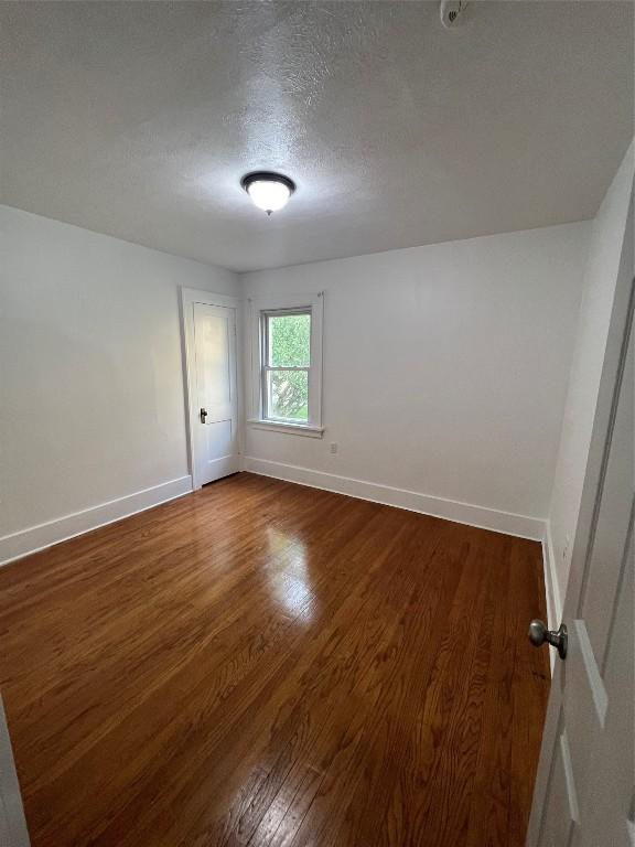 spare room with a textured ceiling and dark hardwood / wood-style floors