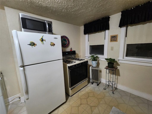 kitchen with radiator heating unit, a textured ceiling, white refrigerator, and gas stove