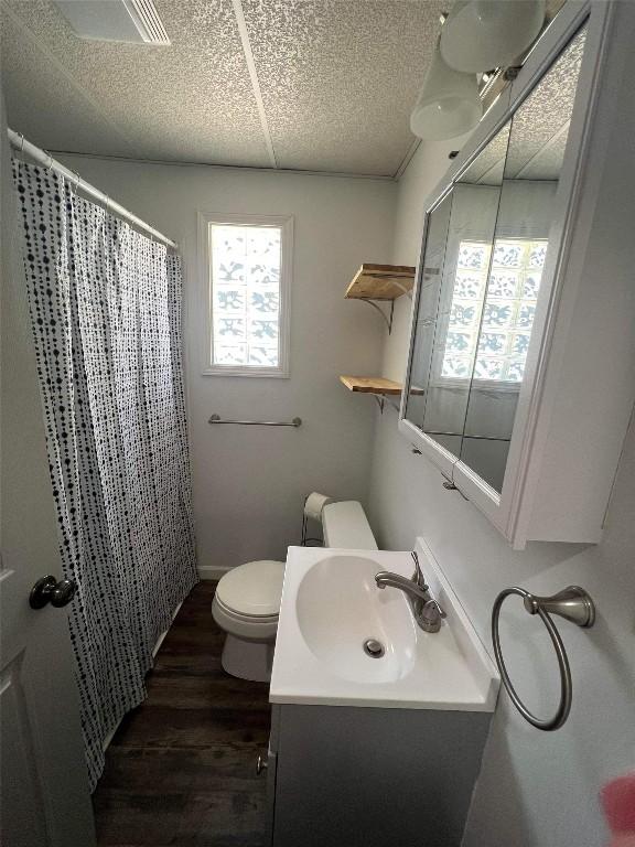 bathroom with wood-type flooring, curtained shower, toilet, and vanity