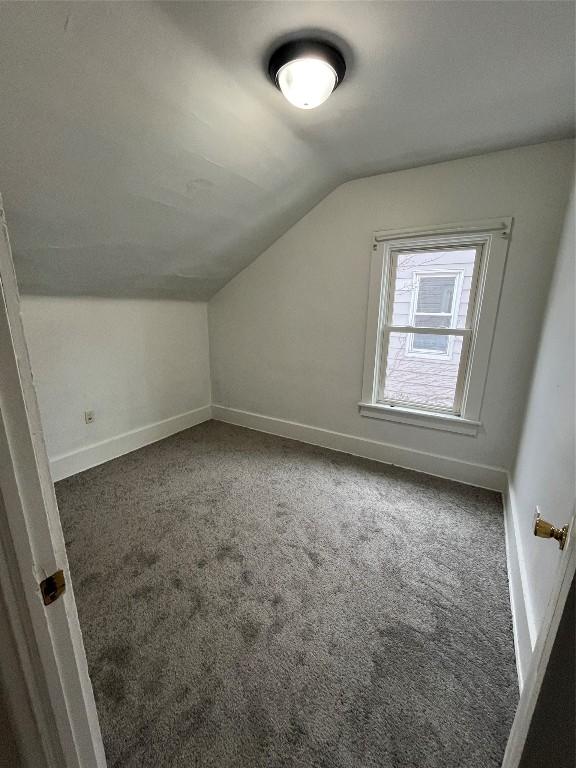 bonus room featuring dark colored carpet and vaulted ceiling