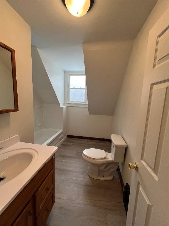 bathroom featuring toilet, vanity, hardwood / wood-style floors, and a bath