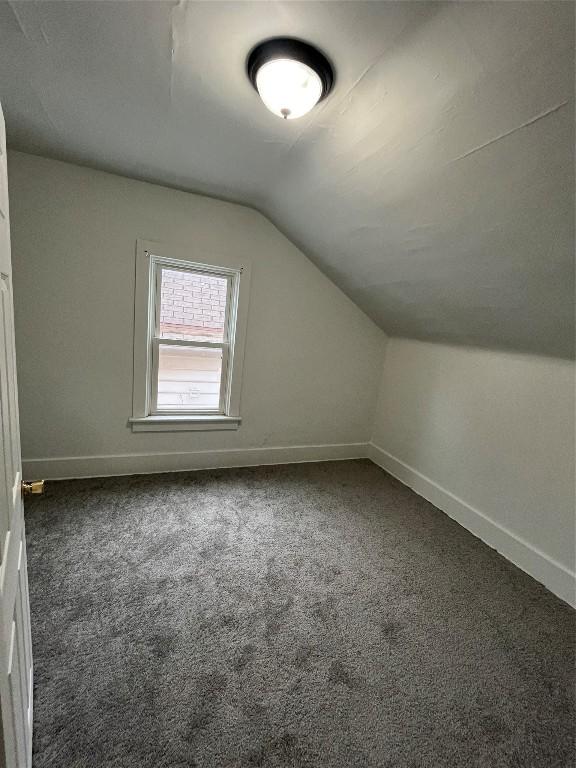 bonus room featuring dark carpet and lofted ceiling