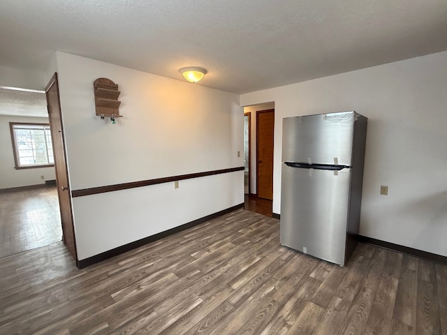 kitchen with dark wood-type flooring, stainless steel refrigerator, and a textured ceiling