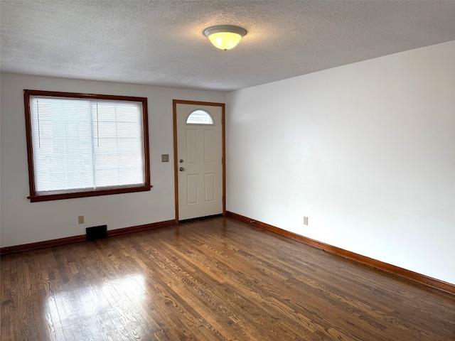 entrance foyer with a textured ceiling and dark hardwood / wood-style flooring