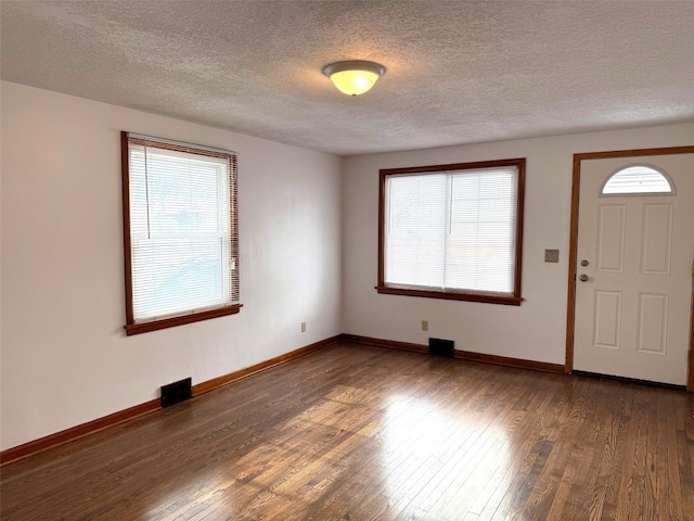 foyer with plenty of natural light, dark hardwood / wood-style floors, and a textured ceiling