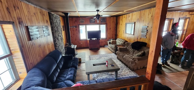 living room featuring ceiling fan, light wood-type flooring, and wood walls