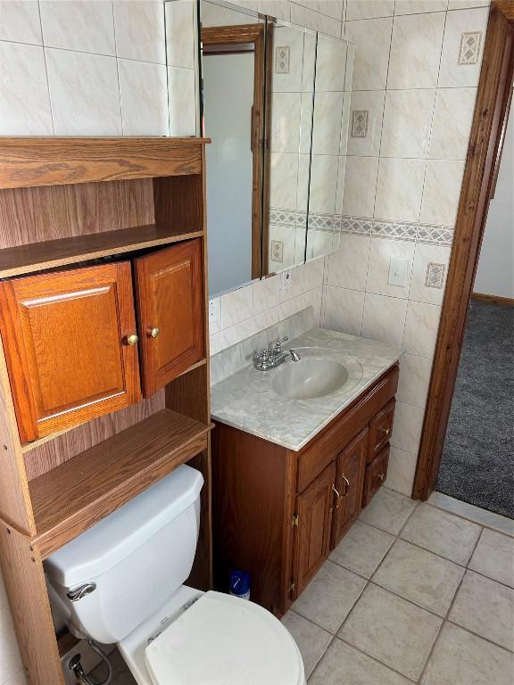 bathroom featuring tile patterned flooring, vanity, tile walls, and toilet