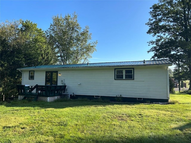 back of house featuring a lawn and a wooden deck