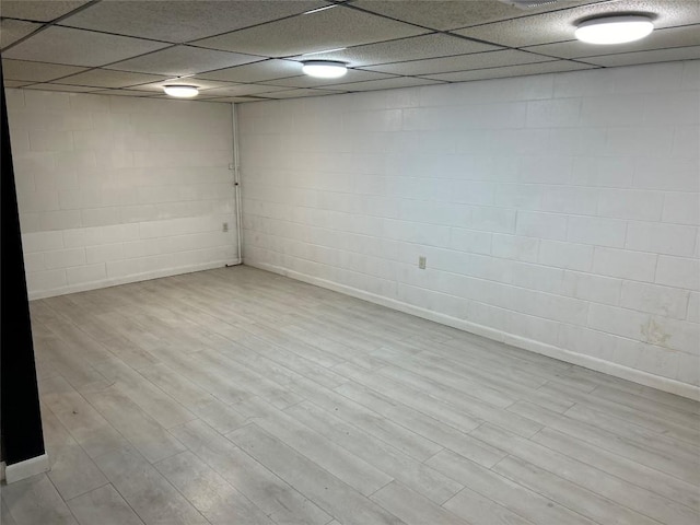 basement featuring a drop ceiling and light hardwood / wood-style flooring