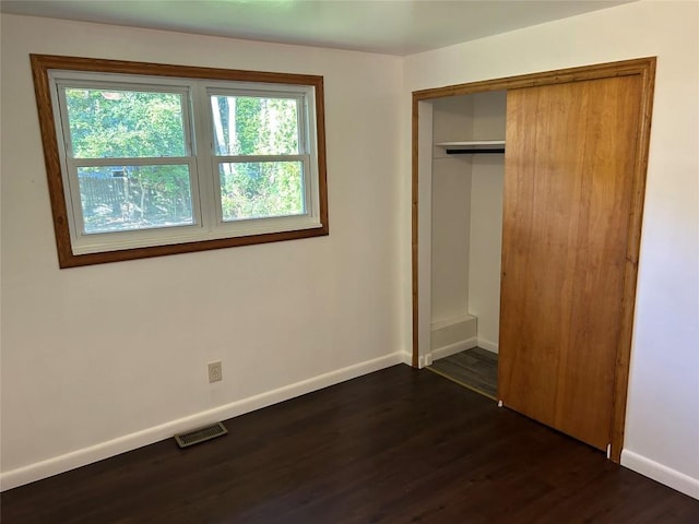 unfurnished bedroom with dark hardwood / wood-style flooring and a closet