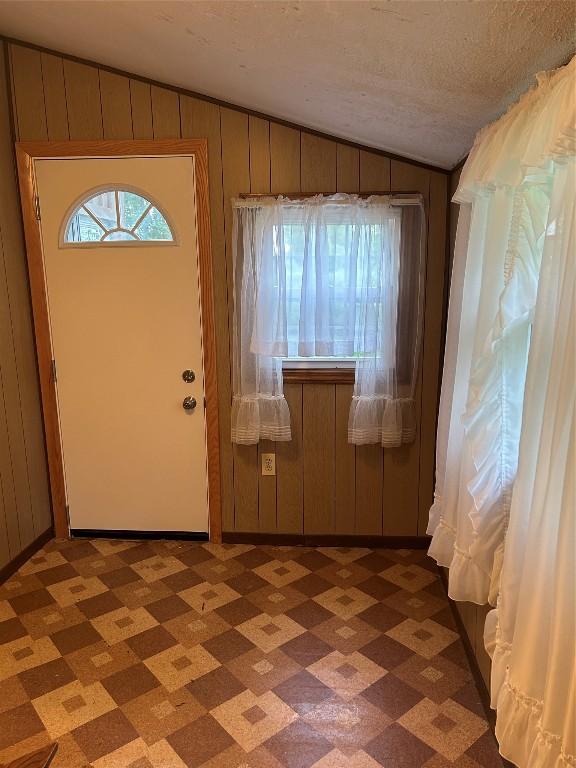 10689 Glenn Blvd, Conneaut Lake, PA 16316 - foyer featuring vaulted ceiling, tile patterned floors, wooden walls, and a textured ceiling