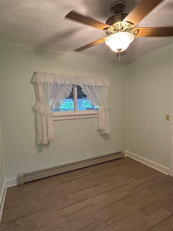 10689 Glenn Blvd, Conneaut Lake, PA 16316 - unfurnished room with baseboard heating, wood finished floors, a ceiling fan, and a textured ceiling