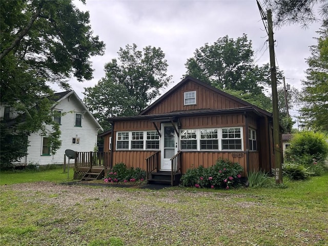 10689 Glenn Blvd, Conneaut Lake, PA 16316 - rear view of house with board and batten siding, a wooden deck, and a lawn