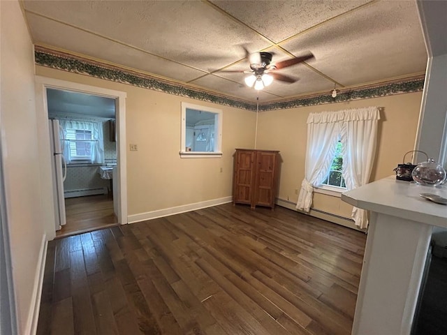 10689 Glenn Blvd, Conneaut Lake, PA 16316 - unfurnished dining area featuring baseboard heating, a textured ceiling, ceiling fan, dark wood-type flooring, and crown molding