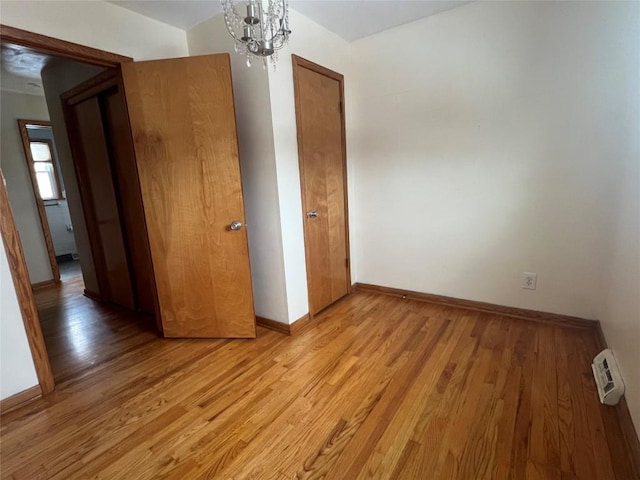 unfurnished bedroom with a notable chandelier and light wood-type flooring